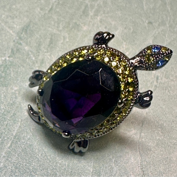 Turtle ring with large purple stone surrounded by green crystals moving head